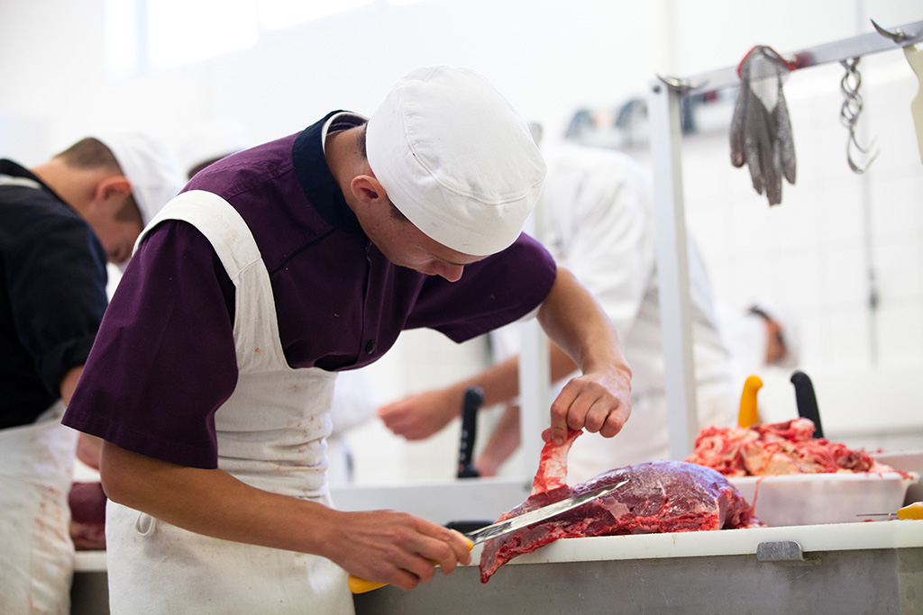 Un apprenti découpe de viande