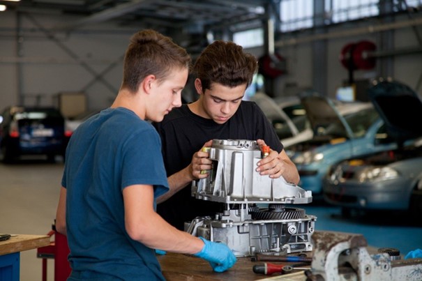 Deux apprentis au dessus d'un moteur de véhicule