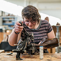 Une jeune femme travaille sur une chaussure en cuir