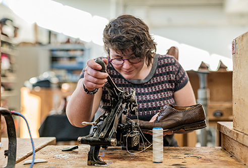Une jeune femme travaille sur une chaussure en cuir