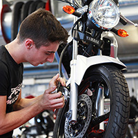 Un jeune homme répare une moto