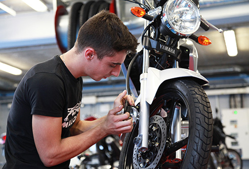 Un jeune homme répare une moto